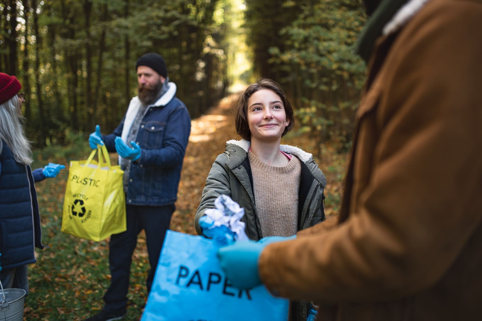 Diverse group of volunteers cleaning up forest from waste, community service concept